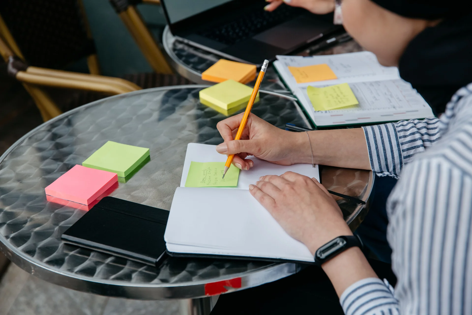 Hands writing on sticky notes